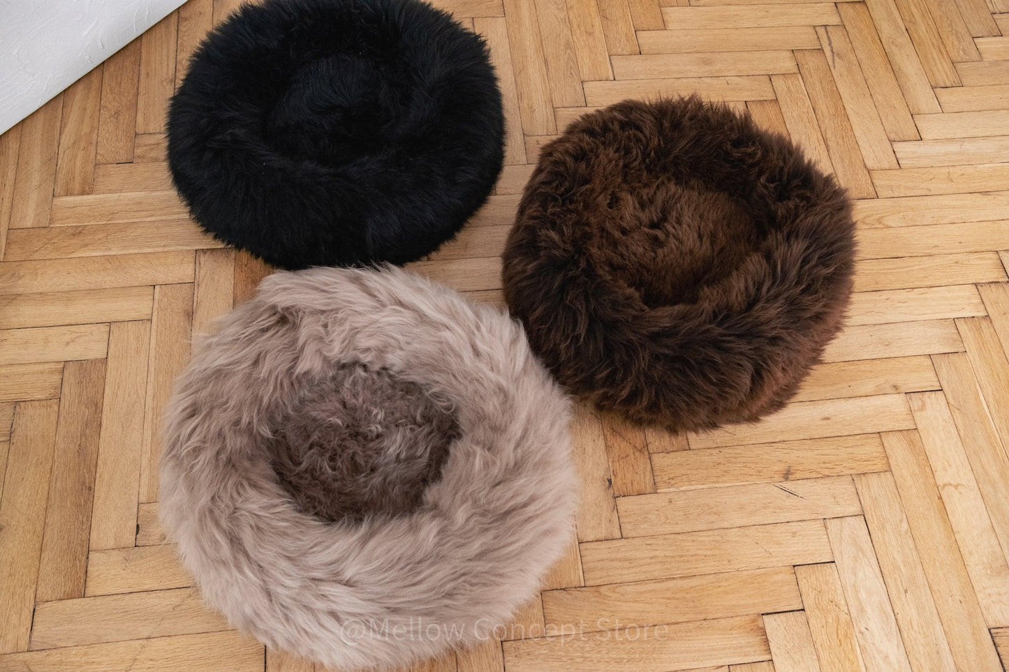 Three Mellow Pet Store Round Natural Sheepskin Pet Beds on a wooden floor.