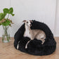A greyhound dog lounges on a plush black Natural Sheepskin Pet Cave made by Mellow Pet Store.