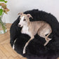 A greyhound lounging on a Mellow Pet Store Natural Sheepskin Pet Cave in black.