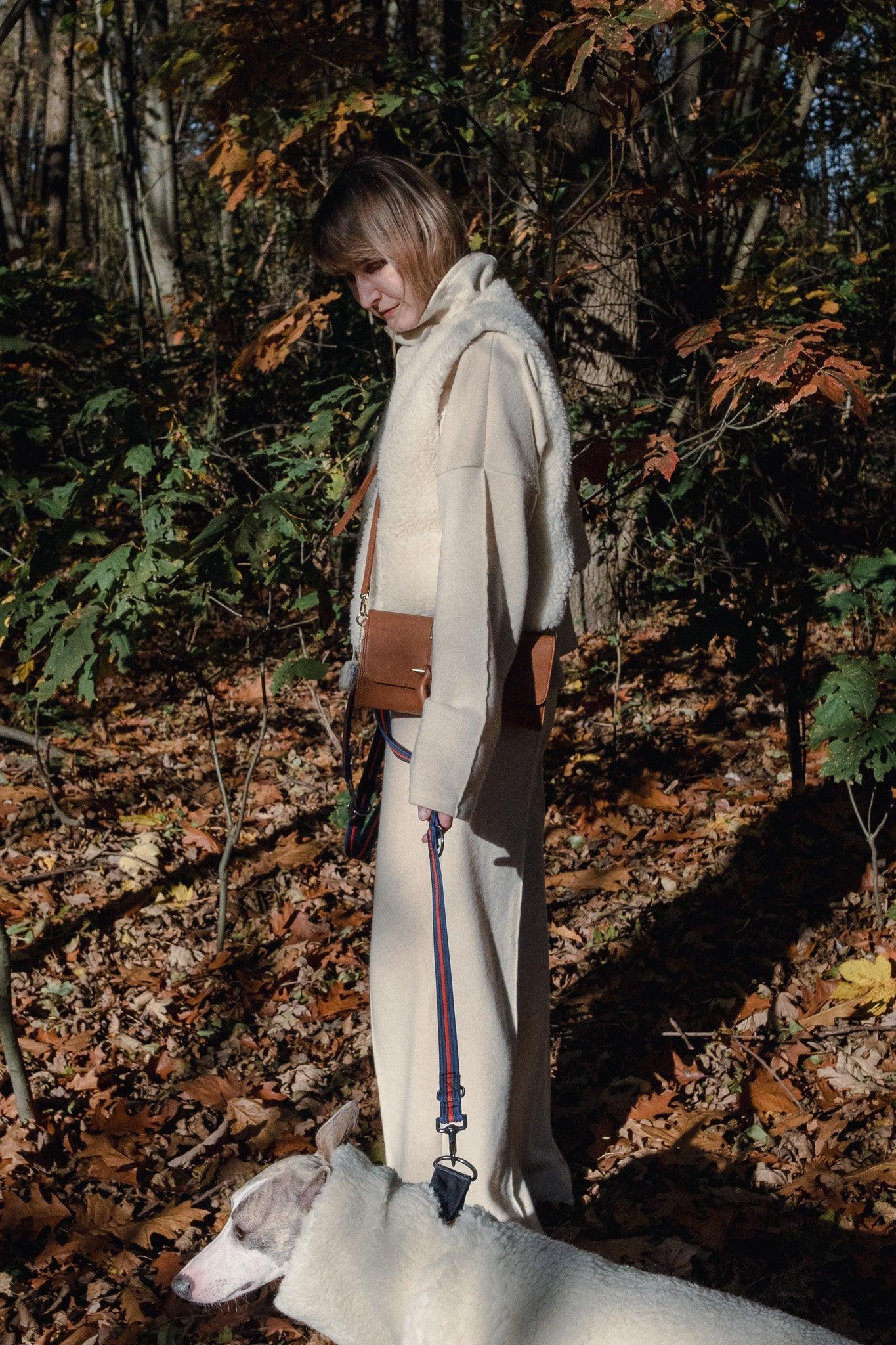 A woman walking her dog in the woods with a Mellow Pet Store Woolen Dog Vest - White.